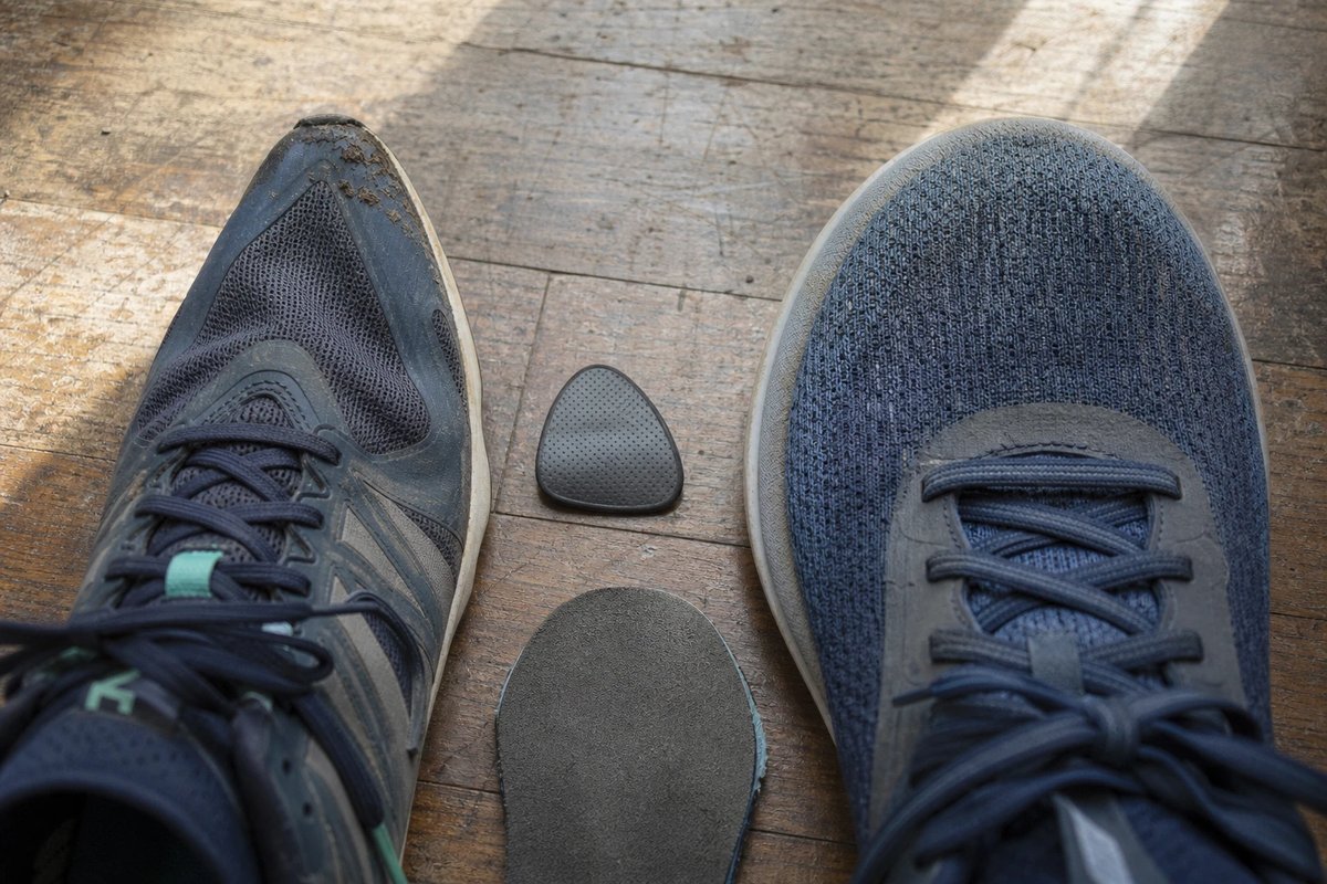 Zwei Laufschuhe von oben nebeneinander, links mit schmaler spitzer Zehenbox, rechts mit breiter runder geräumiger Zehenbox, dazwischen ein tropfenförmiges Mittelfußpolster und eine flache Einlage